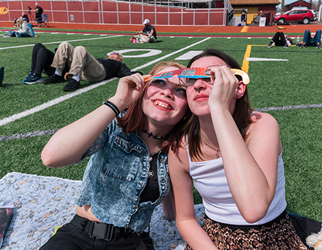 Two people view the eclipse through glasses