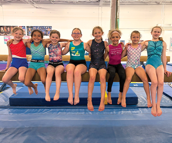 Gymnastics students sitting on beam