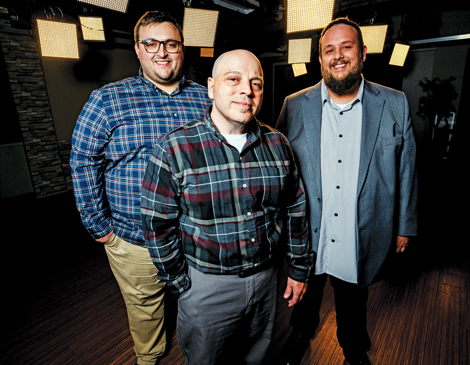 Three men standing in front of lights