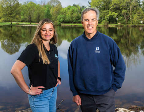 parks-article Brunswick Parks employees Taylor Petkovsek and Tom Adams standing by pond