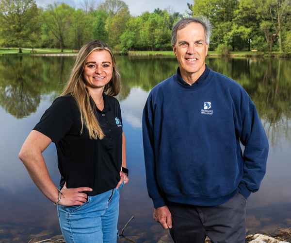 Brunswick Parks employees Taylor Petkovsek and Tom Adams standing by pond