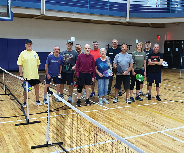 A group of pickleball players smiling on the court