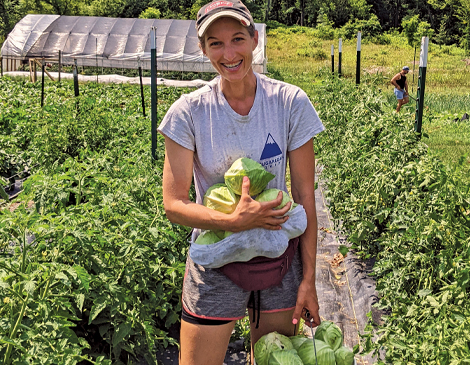 Woman standing in farm field holding vegetables