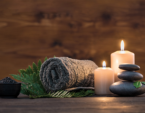 Rolled towel, candles and stones setting a relaxing scene