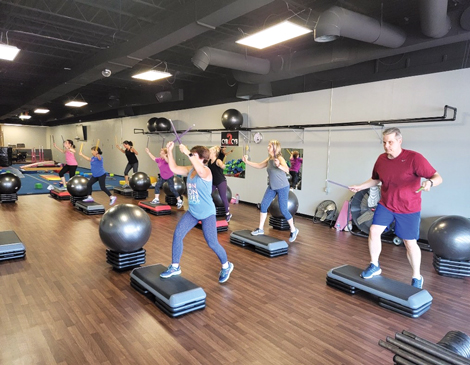 People participating in fitness class with steps and exercise balls