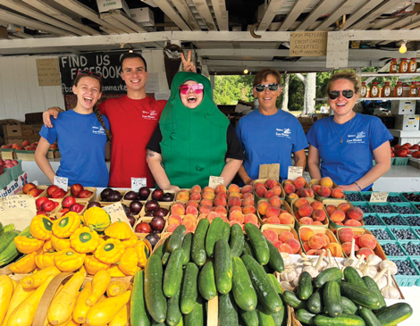 farm market workers standing behind produce