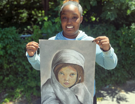 6-Juneteenth-article A young woman holding up a piece of her artwork