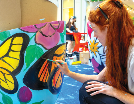 9-mall-murals-article a woman with long red hair painting a colorful butterfly