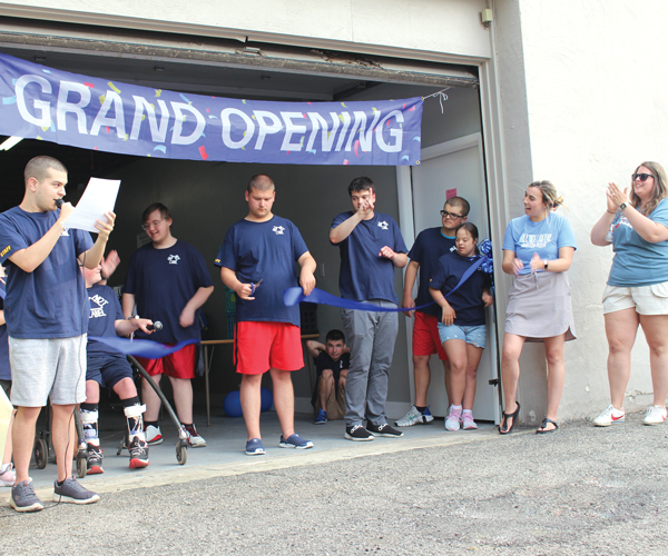 a group of students gathered under a banner that reads "Grand Opening"