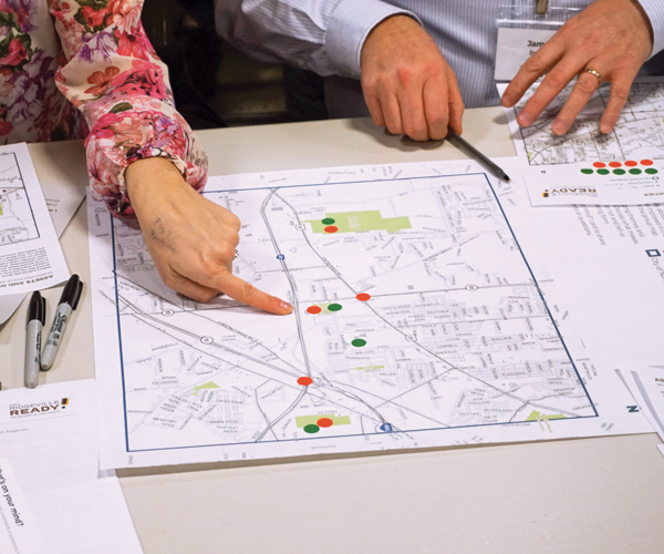 two sets of hands pointing to a map and reviewing documents
