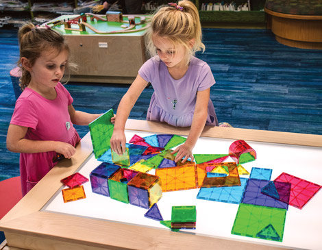 Two young children play with colorful blocks on the light table at Rocky River Public Library