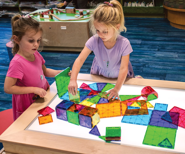Two young children play with colorful blocks on the light table at Rocky River Public Library