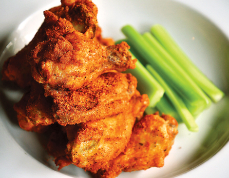 a pile of chicken wings and celery on a white plate