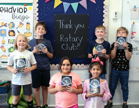 rocky-river-rotary-club-dictionaries-article A group of students holds up dictionaries and poses around a sign that says, "Thank you Rotary Club!"