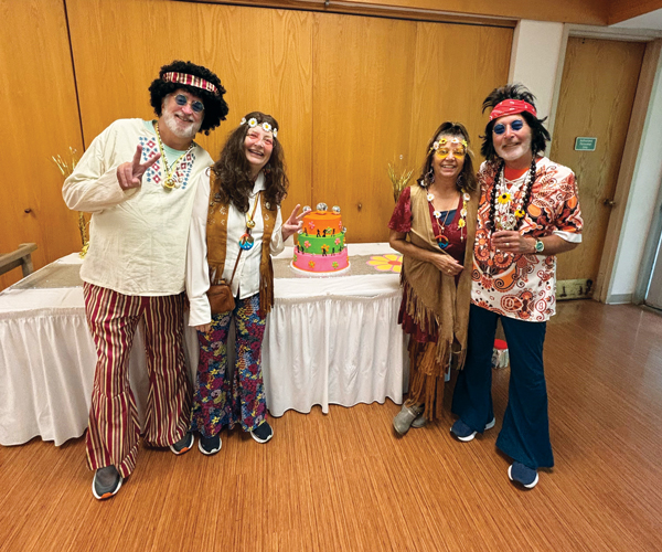 A group of four seniors dressed in 1970s costumes and smiling in the Rocky River Senior Center
