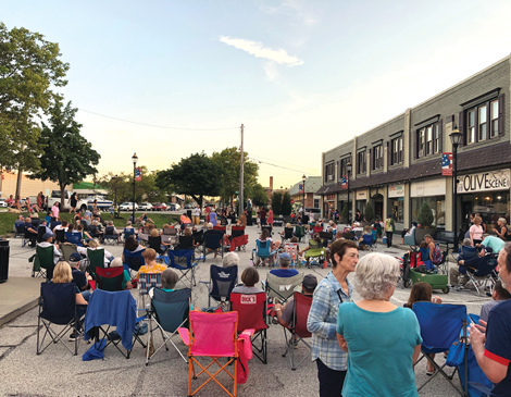 A group of lawn chairs and a crowd of people gathered
