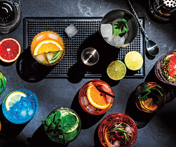 an overhead shot of various cocktails and drink-making tools
