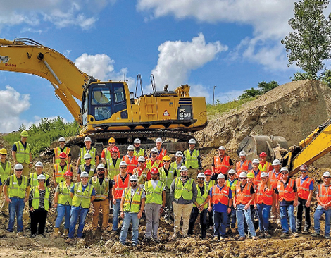 A group of people standing in hard hats and neon vests