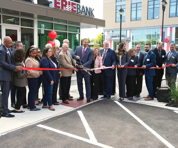 A group of people gathered for a ribbon cutting outside of Erie Bank