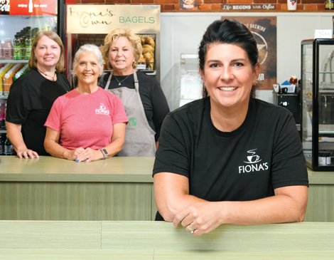 Fionas-Coffee-Bar-Bakery-article Megan Wickline smiling in Fiona's Coffee Bar and Bakery with a group of her employees smiling behind her